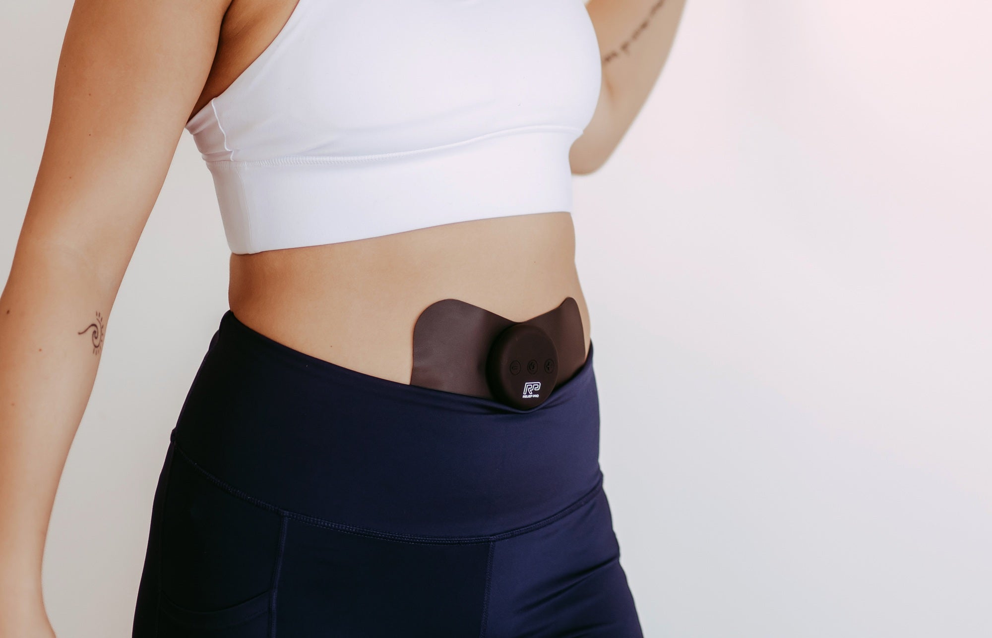 Woman wearing Pro Relief cordless wearable device on lower abdomen — drug-free pain relief.
